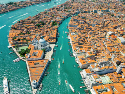 Aerial drone view of Venice, Italy. Water channels with multiple floating and moored boats, historical city centre with Santa Maria della Salute and other old buildings and narrow streets
