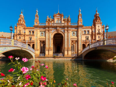 Spain Square or Plaza de Espana in Seville in the sunny summer day, Andalusia, Spain. Flower beds, bridges and channel in the foreground