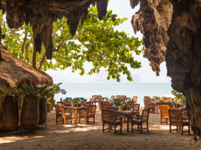 leisure, travel and tourism concept - view to open-air restaurant on beach resort from cave