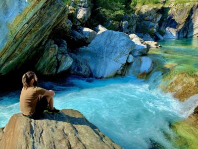 man-sitting-by-pond-rock