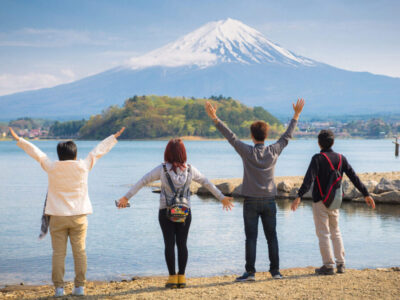 Mt diamond fuji with snow and flower garden along the lake walkway at Kawaguchiko lake in japan, Mt Fuji is one of famous place in Japan. People hands up and looking far away.