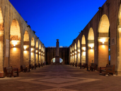 Valletta, Malta, Upper Barrakka Gardens. Illuminated stone arches in the evening, clear dark blue sky.