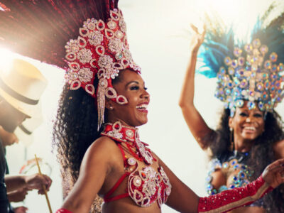Shot of two female dancers wearing vibrant costumes while dancing to music inside of a busy nightclub.