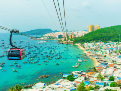 Cable car cabin traveling above turquoise water and fishing boats near An Thoi harbor on Phu Quoc island, Vietnam. Island transportation and tourism infrastructure Modern Hon Thom cable car gondolas.