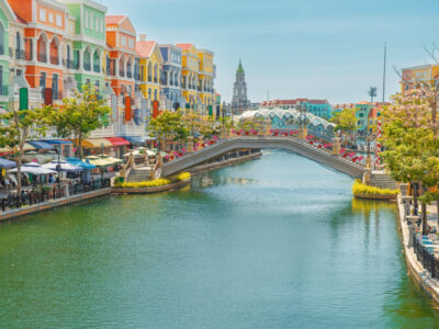 Colorful Venetian style buildings and arched bridge over canal on Phu Quoc island, Vietnam. Grand world city with vibrant cafes, shops and blooming trees. Italian architecture in Asia. Tourism infrastructure in island destinations