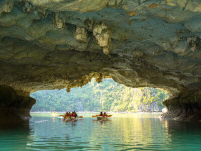 Ha Long, VIETNAM MAR 12 2023: Tourist junks floating among limestone rocks at Ha Long Bay, people kayaking inside of a cave in Lan Ha Bay, close to Halong Bay, Vietnam