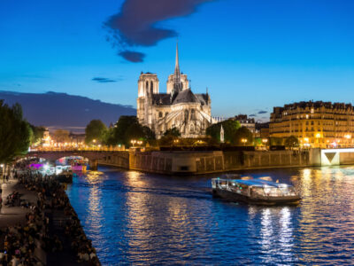 Notre Dame de Paris with cruise ship on Seine river at night in Paris, France
