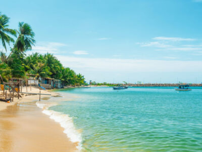 Tropical beach with palm trees turquoise water sea and fishing boats on Phu Quoc island, Vietnam. Summer vacation destination in Asia. Travel and tourism background.